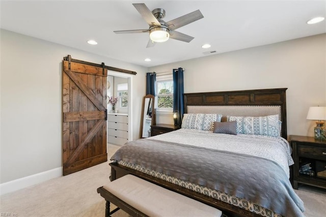 carpeted bedroom with a barn door and ceiling fan