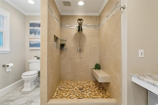 bathroom with toilet, ornamental molding, and tiled shower