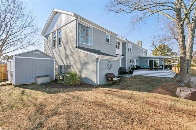 back of house with a lawn, a wooden deck, and a shed