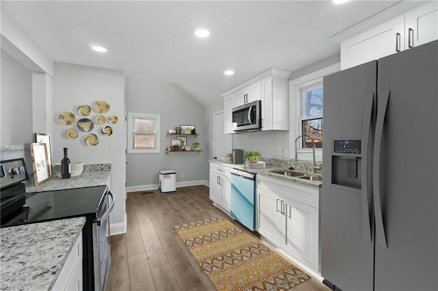 kitchen with appliances with stainless steel finishes, light stone counters, dark wood-type flooring, sink, and white cabinetry