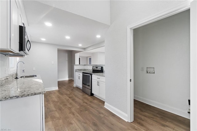 kitchen with dark hardwood / wood-style flooring, light stone counters, stainless steel range with electric stovetop, sink, and white cabinets