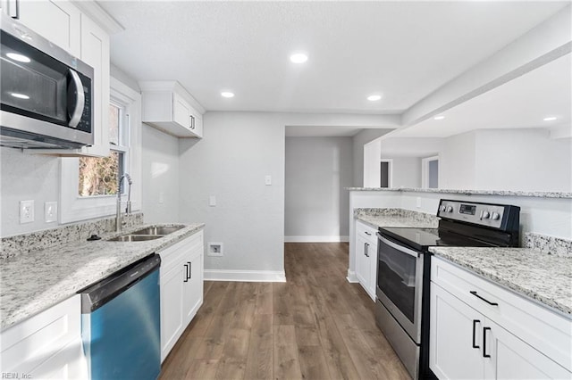 kitchen featuring light stone counters, stainless steel appliances, dark wood-type flooring, sink, and white cabinets