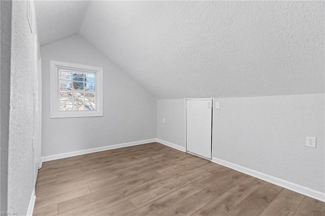 bonus room with hardwood / wood-style flooring, lofted ceiling, and a textured ceiling