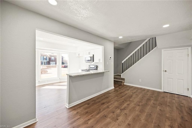 kitchen with kitchen peninsula, electric range oven, white cabinetry, and dark wood-type flooring