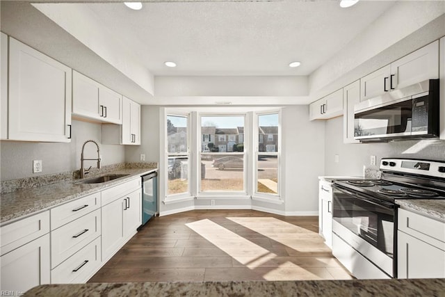 kitchen with light stone counters, sink, white cabinets, and appliances with stainless steel finishes