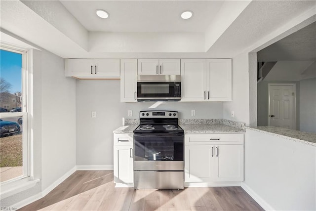 kitchen with light stone counters, white cabinets, and stainless steel appliances