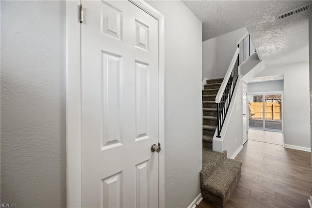 stairway with hardwood / wood-style floors and a textured ceiling