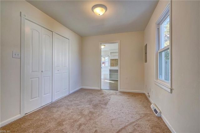 unfurnished bedroom with light colored carpet, electric panel, and a closet