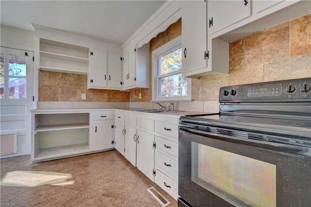 kitchen with sink, light tile patterned floors, black range with electric cooktop, decorative backsplash, and white cabinets