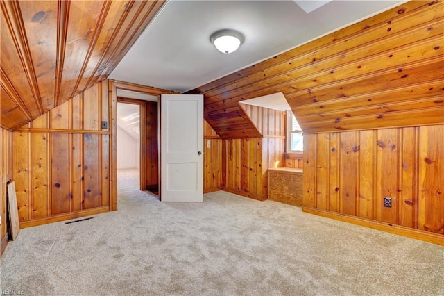 additional living space with lofted ceiling, light carpet, and wooden walls