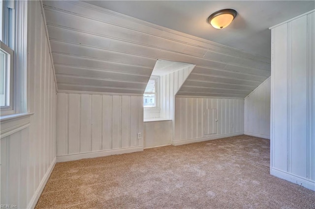 additional living space featuring light colored carpet and vaulted ceiling