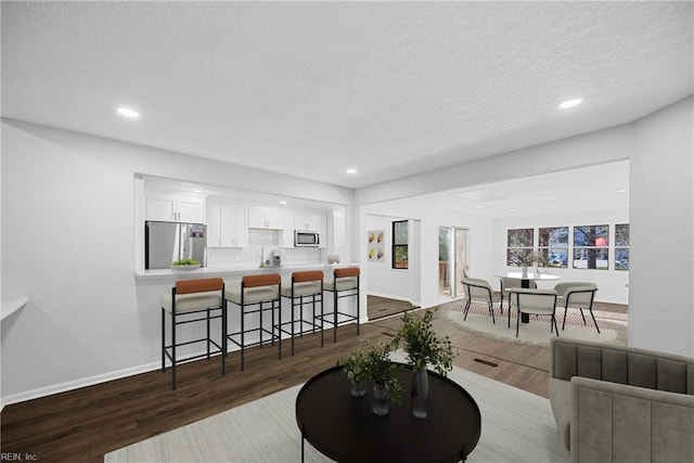 living room with a textured ceiling, sink, and dark hardwood / wood-style floors