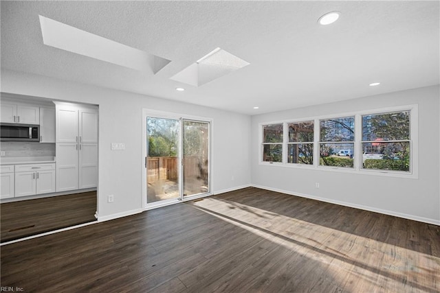 unfurnished living room featuring dark wood-type flooring and a skylight