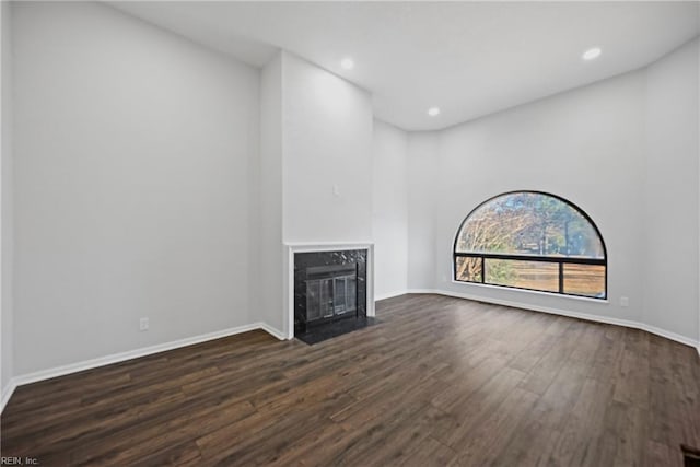 unfurnished living room featuring dark wood-type flooring and a premium fireplace