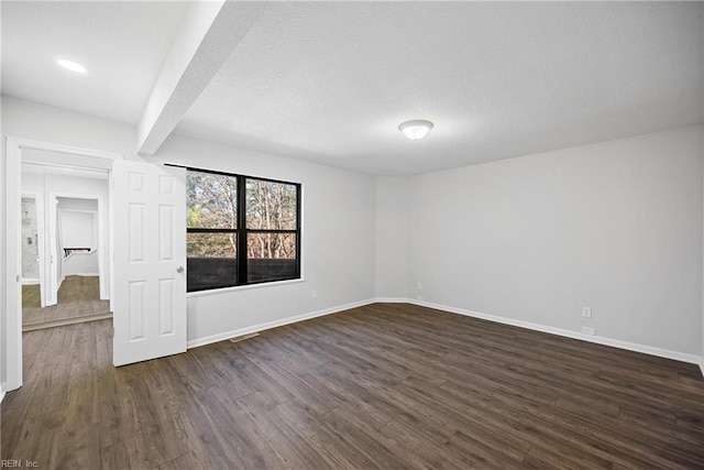 empty room featuring beam ceiling and dark hardwood / wood-style flooring