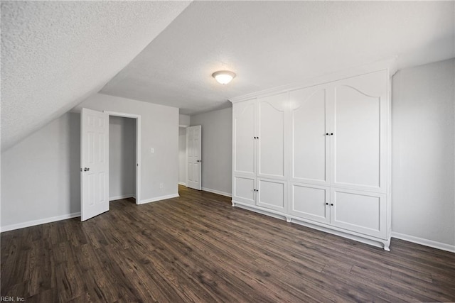 additional living space featuring vaulted ceiling, a textured ceiling, and dark hardwood / wood-style floors