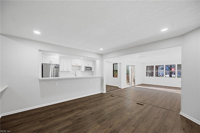 unfurnished living room with a textured ceiling and dark hardwood / wood-style floors