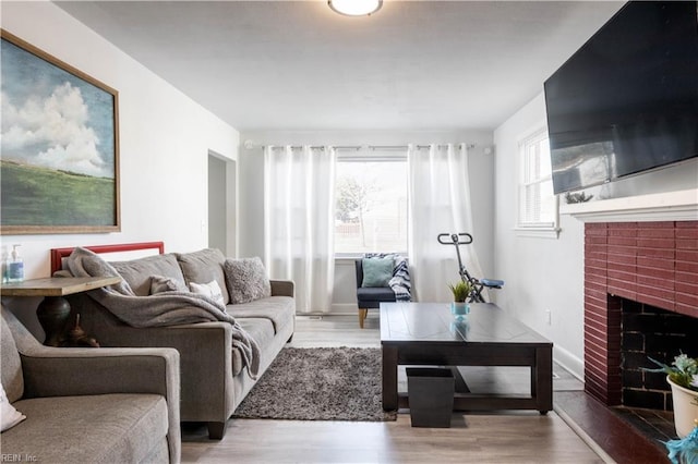 living room featuring light hardwood / wood-style floors and a brick fireplace