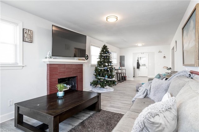 living room with light wood-type flooring and a brick fireplace