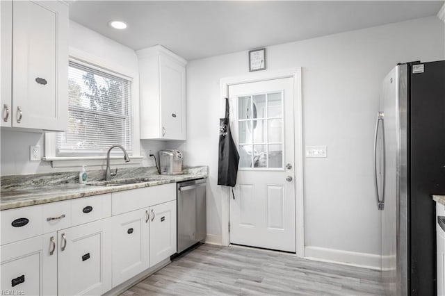 kitchen with white cabinets, sink, light hardwood / wood-style floors, light stone counters, and stainless steel appliances