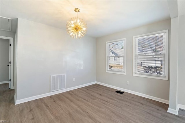 unfurnished room featuring a chandelier and hardwood / wood-style flooring