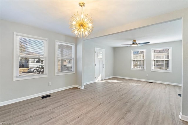 spare room with ceiling fan with notable chandelier and light hardwood / wood-style flooring