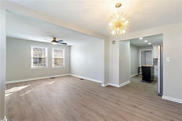 empty room featuring wood-type flooring and ceiling fan with notable chandelier