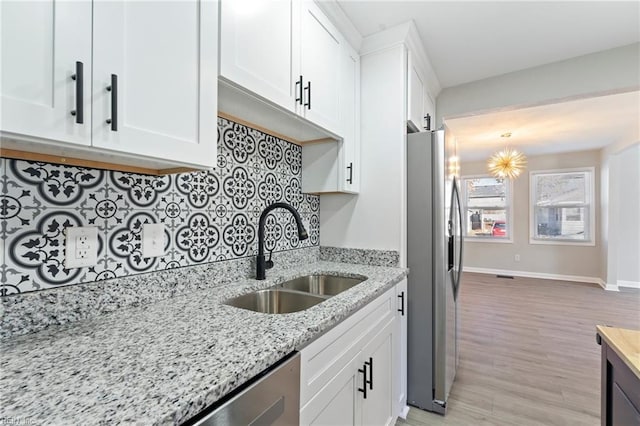 kitchen featuring white cabinets, sink, light stone countertops, a notable chandelier, and stainless steel appliances