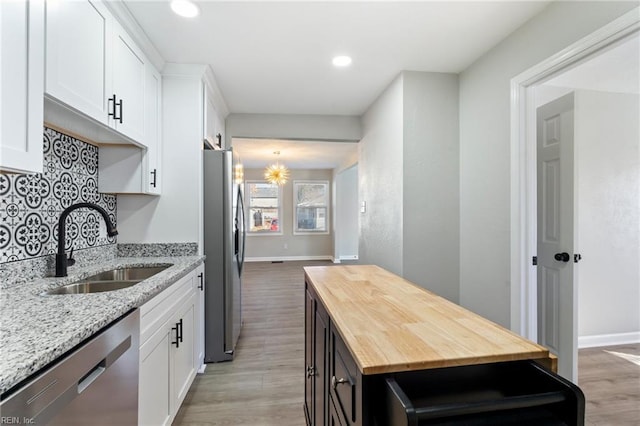 kitchen with light stone countertops, appliances with stainless steel finishes, white cabinetry, and sink