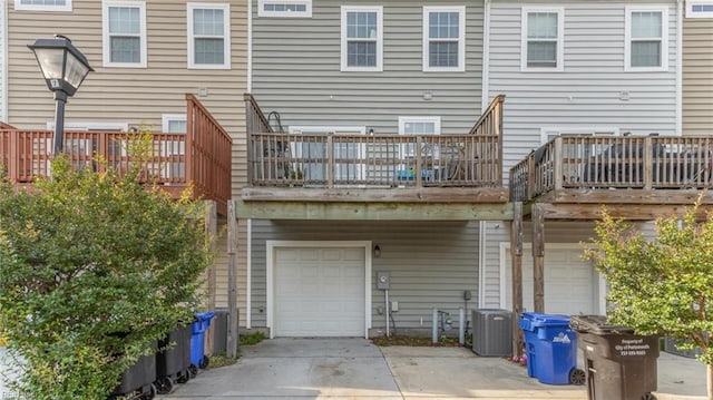 back of house with central air condition unit, a balcony, and a garage