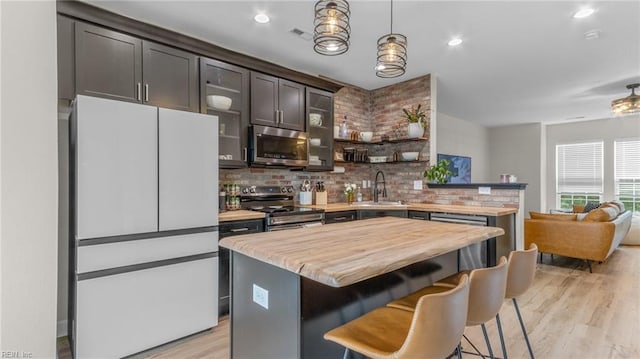 kitchen with a breakfast bar area, sink, light hardwood / wood-style flooring, and appliances with stainless steel finishes