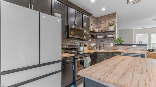 kitchen with appliances with stainless steel finishes, tasteful backsplash, dark brown cabinetry, sink, and butcher block counters