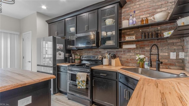 kitchen featuring wood counters, decorative backsplash, stainless steel appliances, and sink