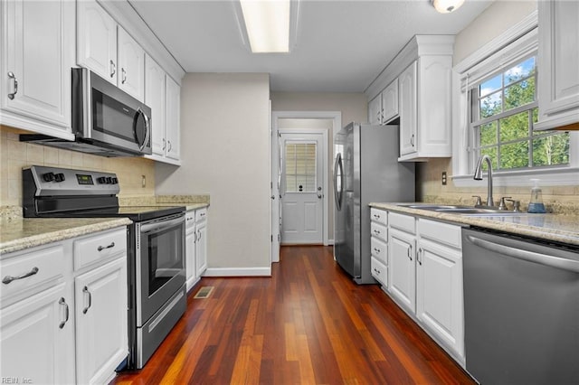 kitchen featuring light stone counters, stainless steel appliances, white cabinetry, and sink