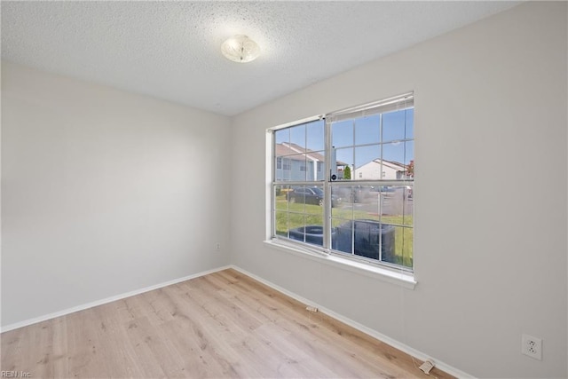 empty room with light hardwood / wood-style floors and a textured ceiling