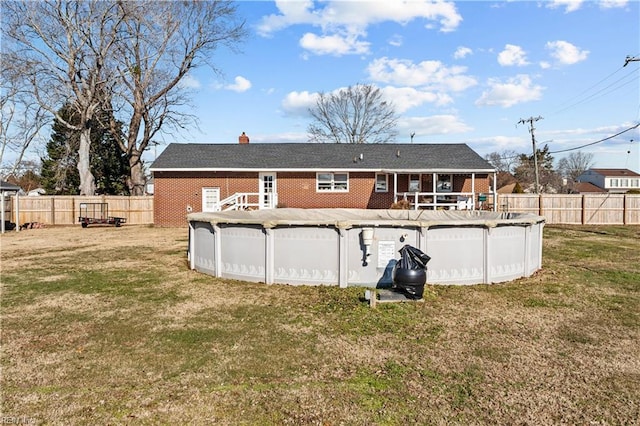 rear view of house featuring a lawn and a covered pool