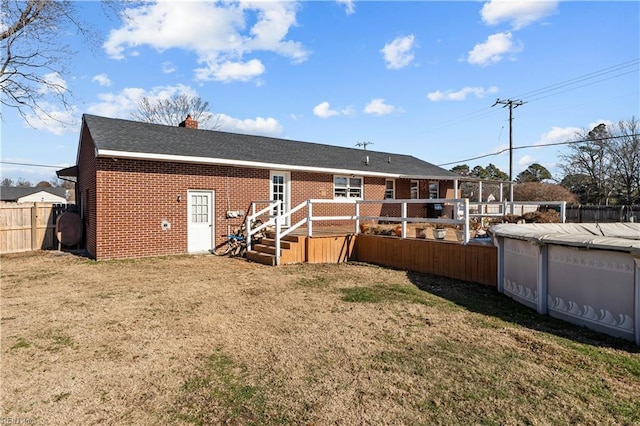 rear view of house with a covered pool and a lawn