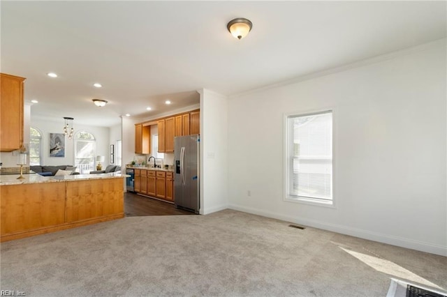 kitchen with sink, kitchen peninsula, carpet flooring, ornamental molding, and stainless steel fridge with ice dispenser