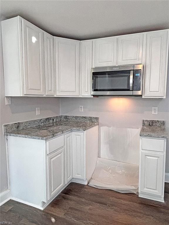 kitchen with white cabinets, dark hardwood / wood-style flooring, and stone countertops