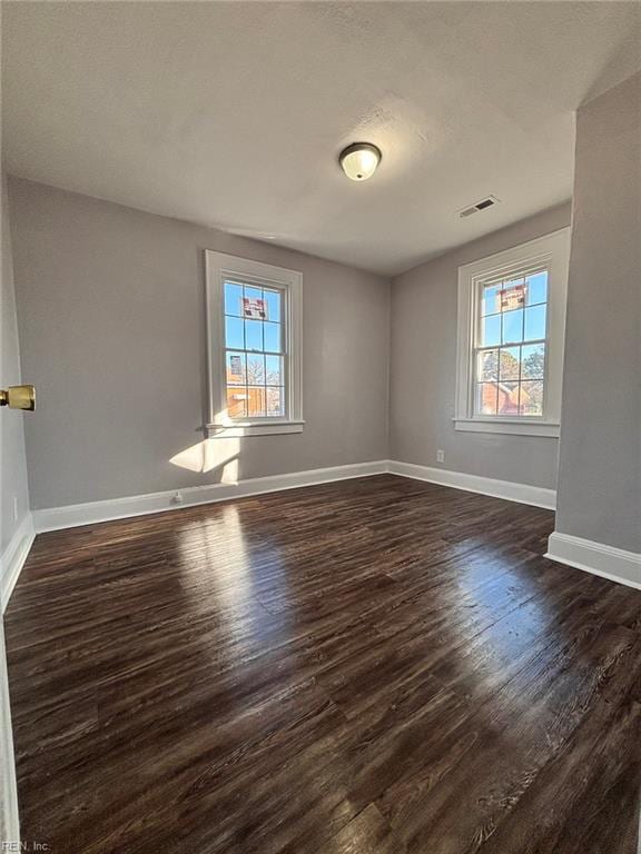 empty room with a healthy amount of sunlight and dark hardwood / wood-style floors