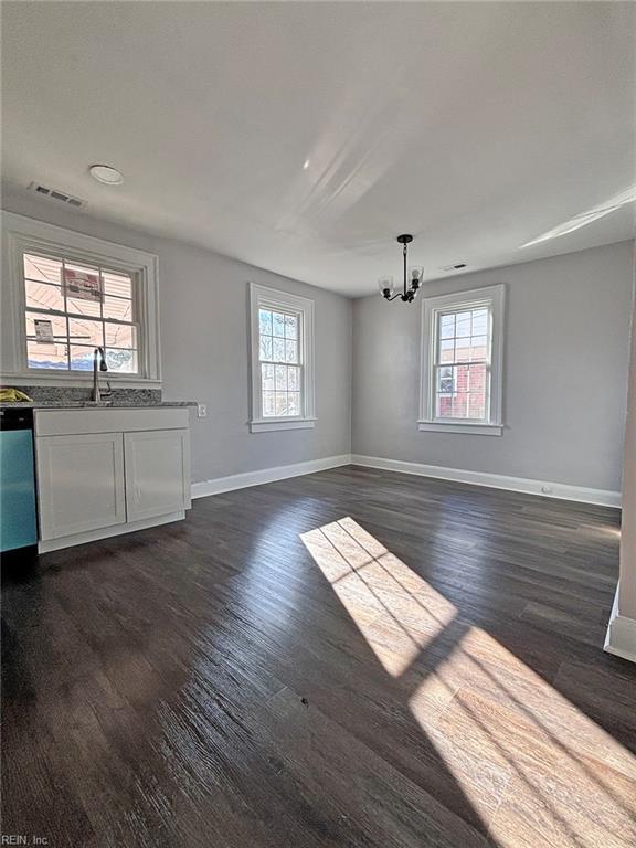 unfurnished living room featuring a notable chandelier and dark hardwood / wood-style flooring