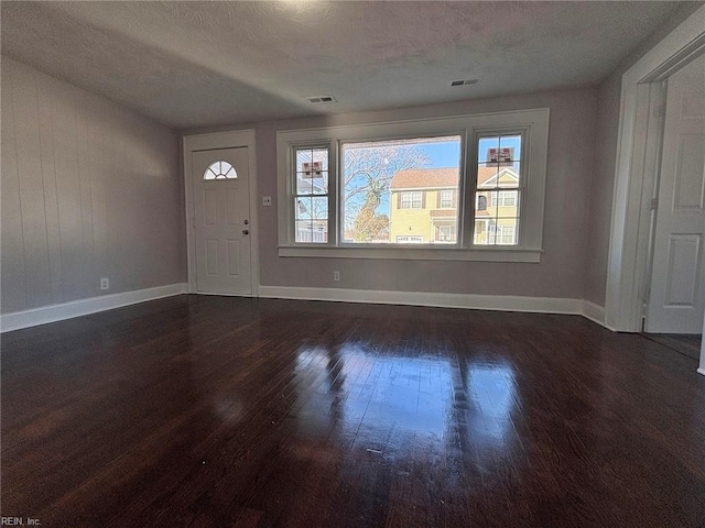 foyer entrance with dark hardwood / wood-style floors and a textured ceiling