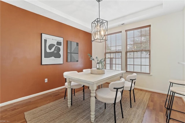 dining room featuring hardwood / wood-style floors, a notable chandelier, and a raised ceiling