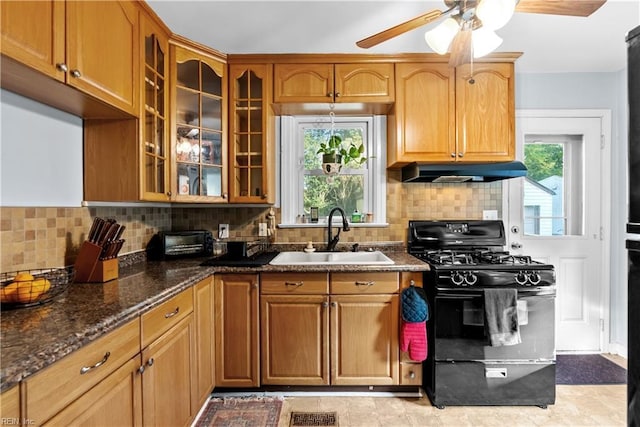 kitchen with ceiling fan, sink, black gas stove, dark stone counters, and decorative backsplash