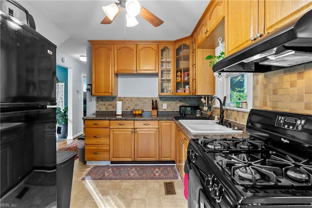 kitchen featuring decorative backsplash, dark stone counters, ceiling fan, sink, and black gas stove