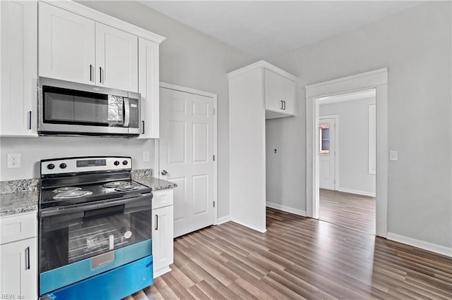 kitchen with white cabinets, dark hardwood / wood-style flooring, light stone counters, and electric stove