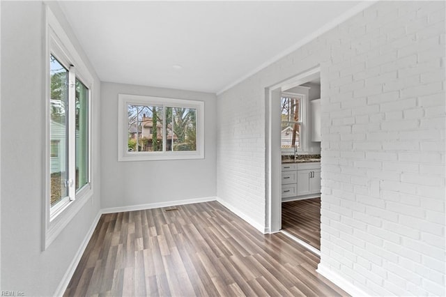 empty room with sink, hardwood / wood-style flooring, and brick wall