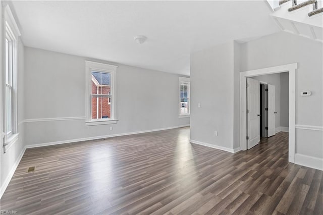 empty room featuring a healthy amount of sunlight, dark hardwood / wood-style flooring, and lofted ceiling