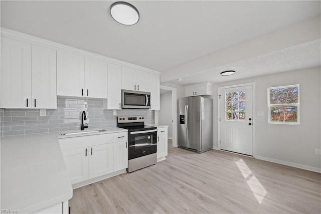 kitchen with backsplash, sink, white cabinets, and appliances with stainless steel finishes