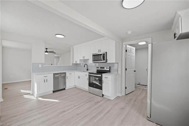 kitchen featuring ceiling fan, tasteful backsplash, appliances with stainless steel finishes, white cabinets, and light wood-type flooring